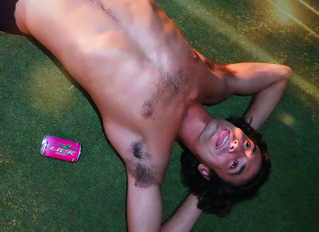 A man lying on grass with a can of Razzade Lick Energy drink.