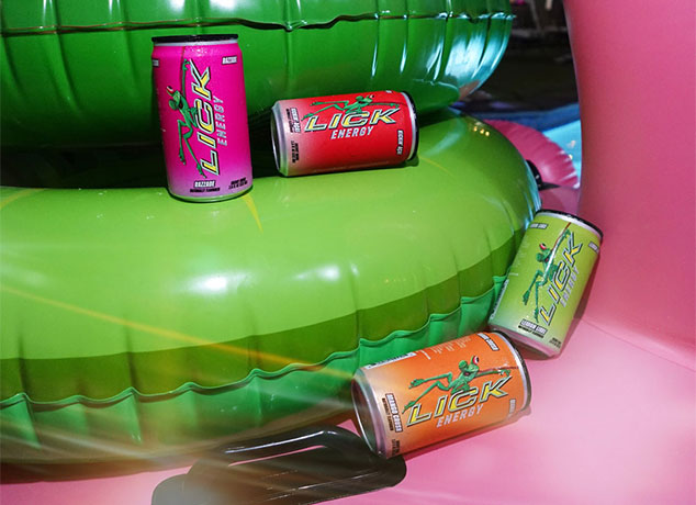 Four Lick Energy drink cans on green and pink inflatable pool floats.