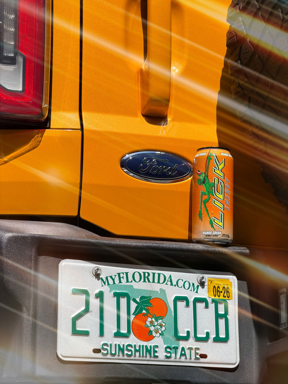 Yellow vehicle with a can of Mango Crush Lick Energy on the tailgate.