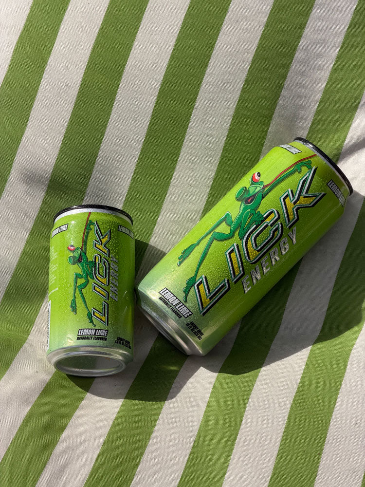 Two cans of Lick Energy drink on a green and white striped surface
