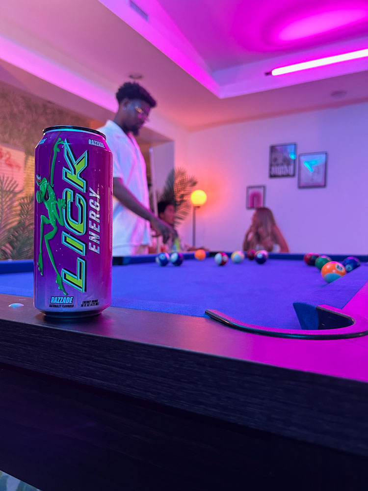 LICK Energy drink can on a pool table with people in the background