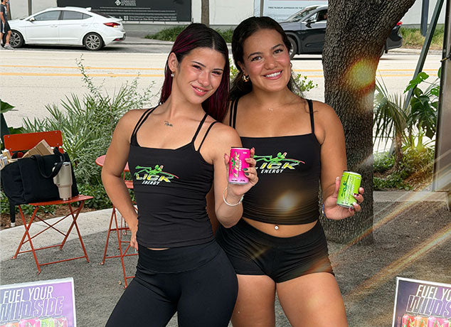 Two brand ambassadors holding Lick Energy drinks at an event.
