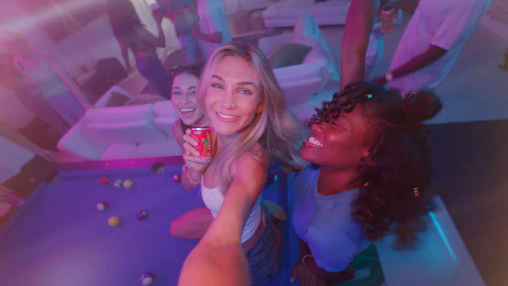 Three friends taking a selfie in a pool hall with pool balls on the floor with LICK Energy