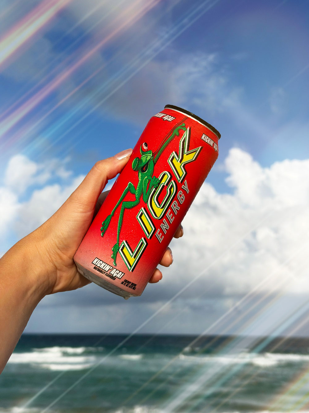 LICK energy drink can held by a hand with a blue sky and ocean background