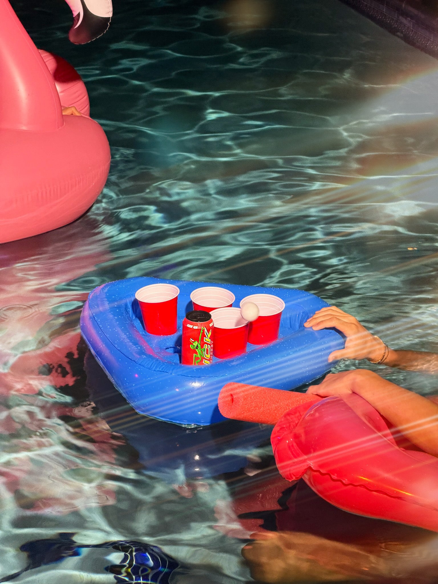 Blue pool float with red cups and bottles in a swimming pool with LICK Energy