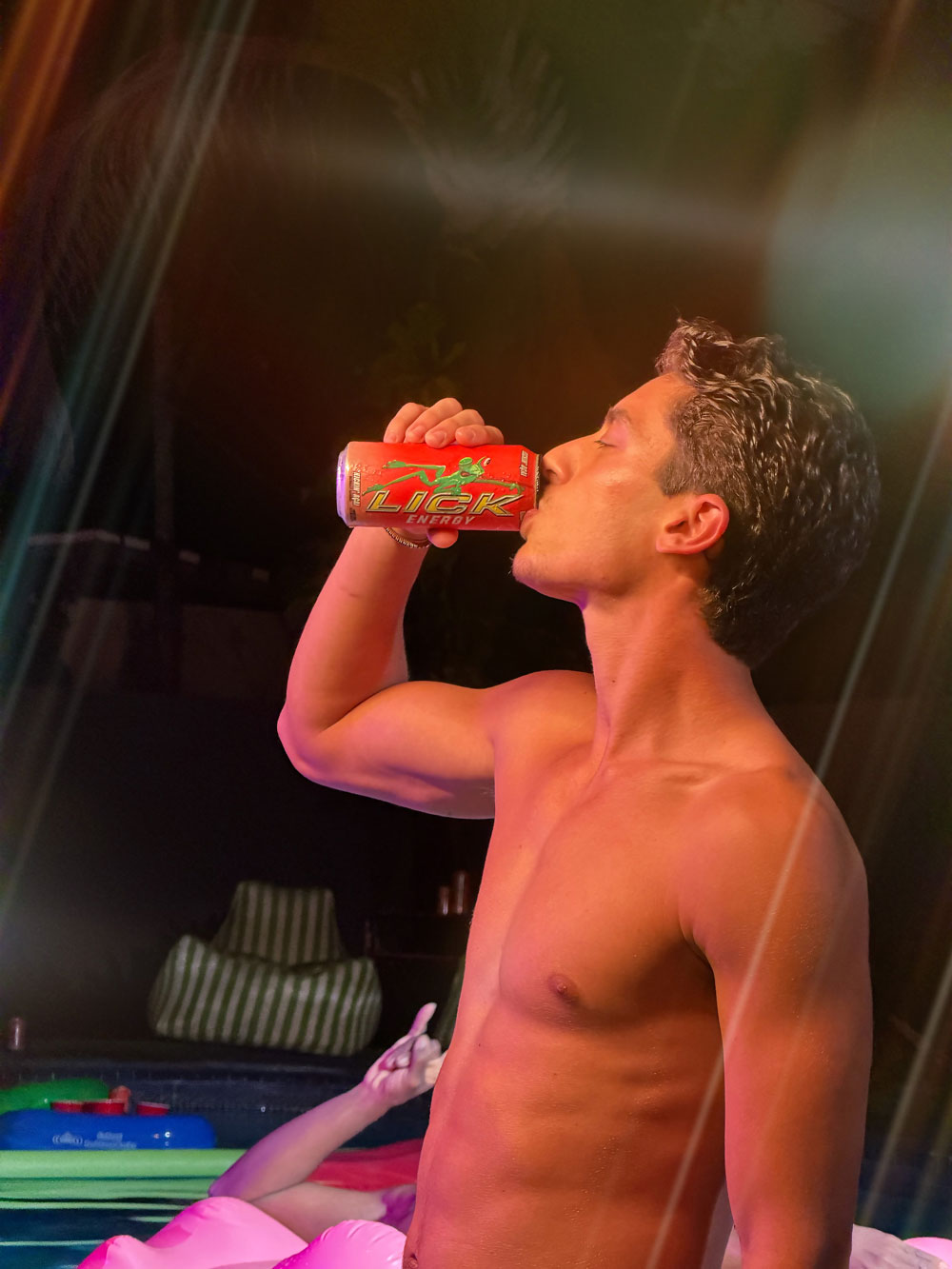 Man drinking from a red LICK Energy drink can with a blurred background
