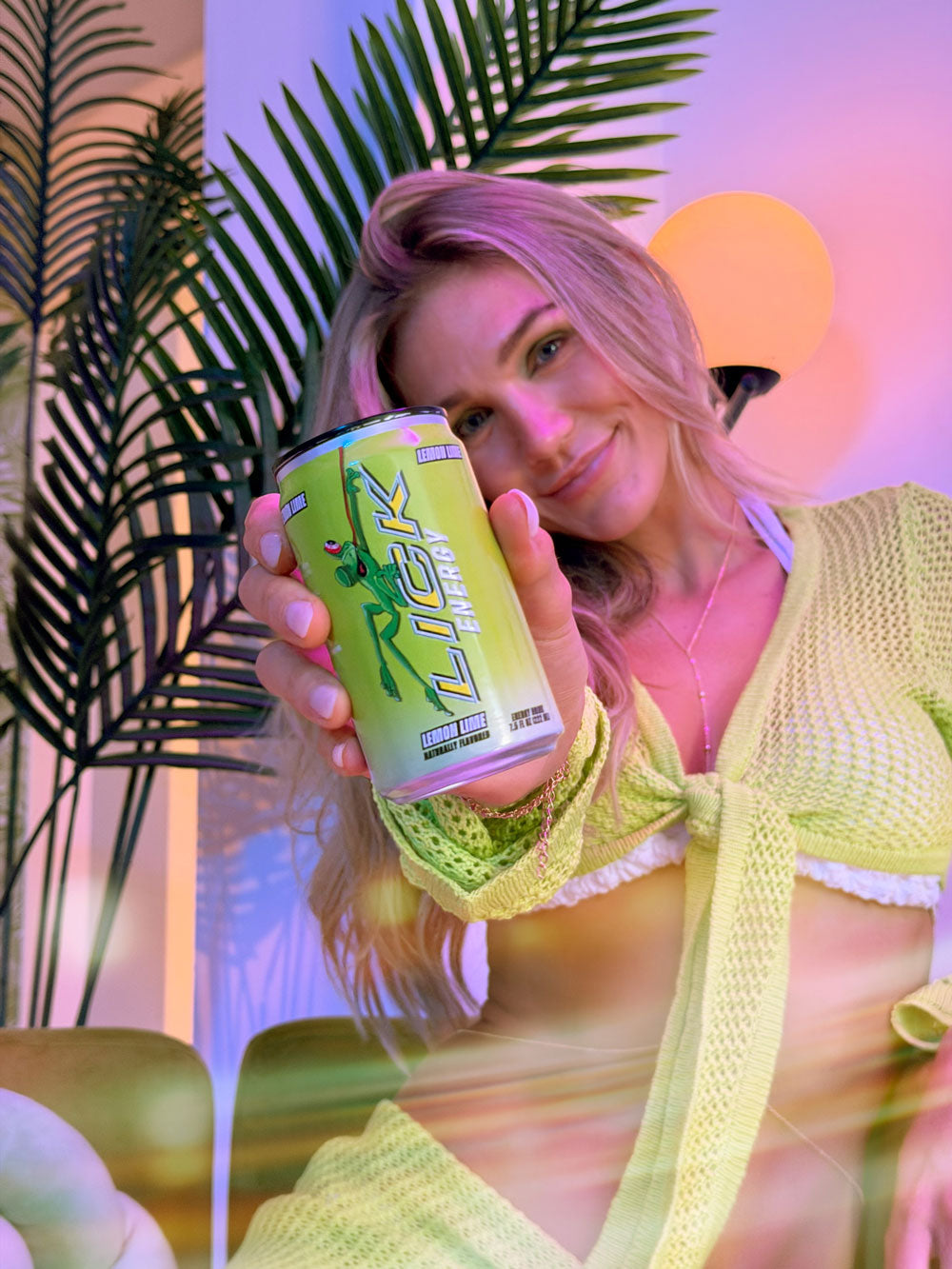Woman holding a can of LICK Energy in a tropical setting